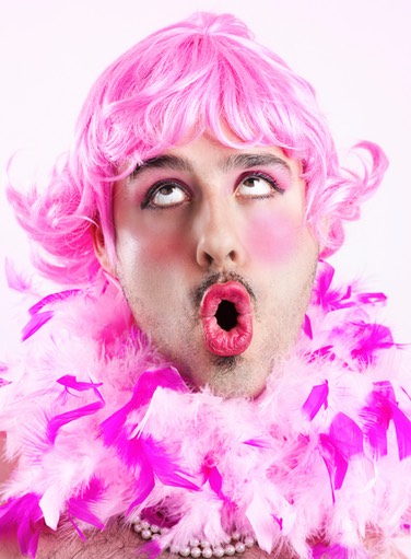 Man dressed in a pink wig and fluffy necklace pulling a funny face