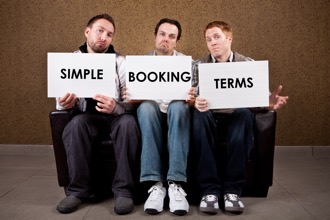 3 men sat on a sofa holding cards up showing simple booking terms